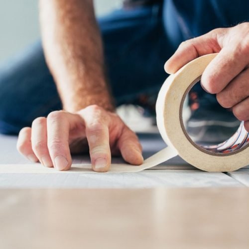 Floating flooring foreman glues foam polystyrene backing sheets with adhesive tape